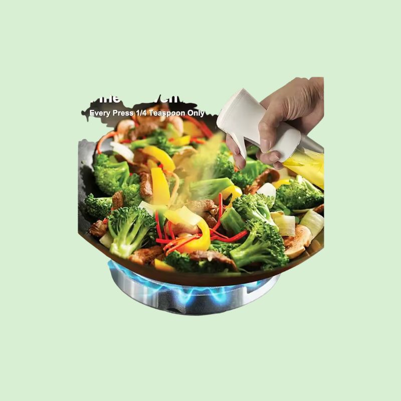 Pulvérisateur d’huile en inox vaporisant de l’huile sur une salade fraîche