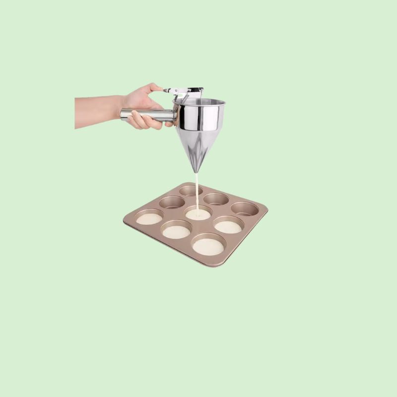 Distributeur de pâte en inox en train de verser de la pâte dans des moules à pâtisserie