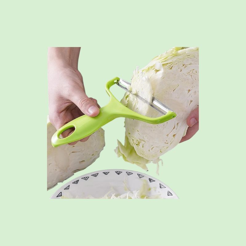 Éplucheur en acier inoxydable en train de râper du chou blanc, montrant l’efficacité et la facilité d’utilisation du produit.