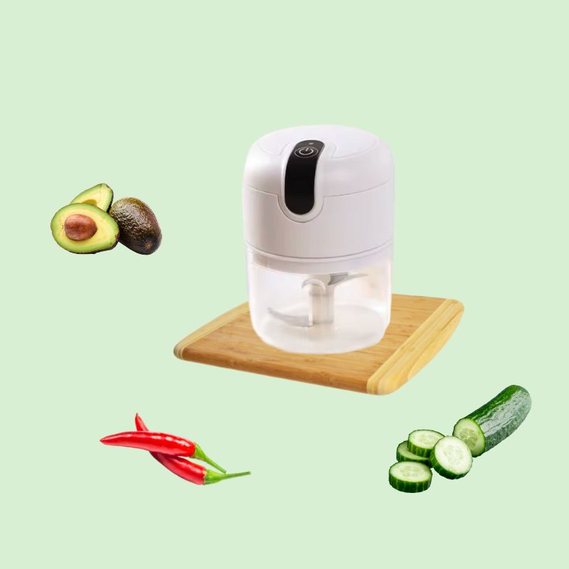 Hachoir électrique multifonction vide sur un plan de travail, entouré de légumes frais comme concombre, avocat et piment rouge