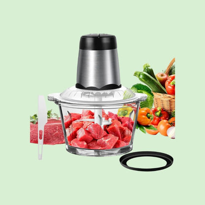 Hachoir à viande électrique multifonction rempli de morceaux de viande avec des légumes frais à côté