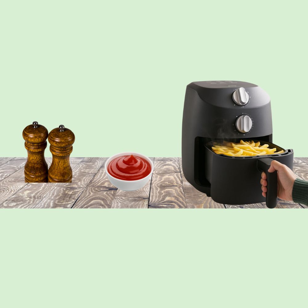 Mini friteuse compacte air fryer sur plan de cuisine, cuisson de frites avec ketchup à côté