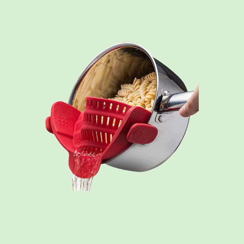 Passoire silicone clip rouge en train d'égoutter des pâtes