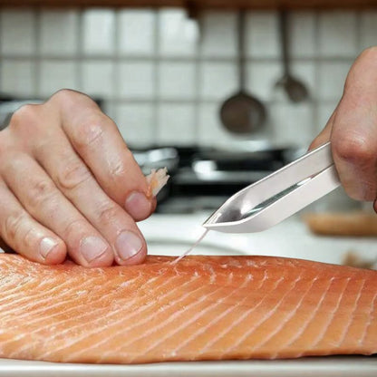 Pince à arêtes en acier inox montrée à côté d’un poisson frais