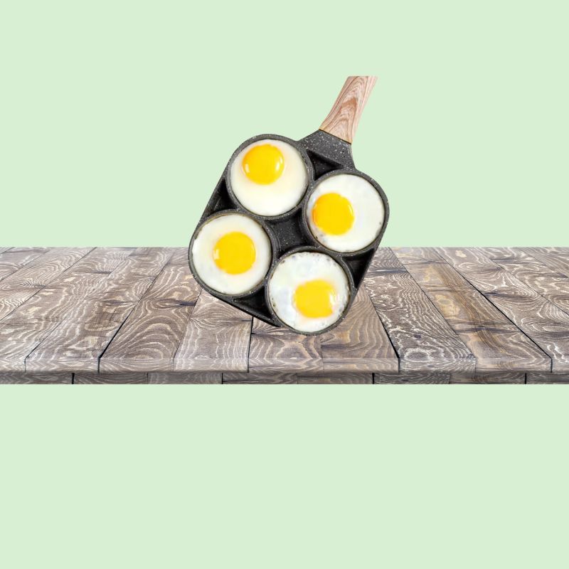 Poêle 4 trous antiadhésive avec omelettes sur un plan de travail de cuisine
